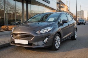 Szary Ford Fiesta zaparkowany przed salonem samochodowym przy ulicy